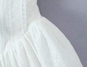 Detailaufnahme der weißen Spitzenstickerei und der floralen Falten an der Taille