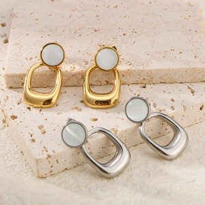Macro detail of 18K gold and silver cat's eye stone pendant earrings on stone