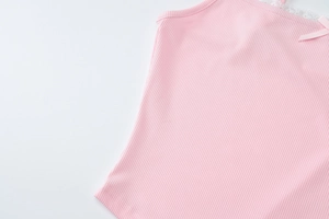 Macro detail of pink ribbed knit camisole featuring white lace trim and a delicate bow