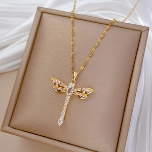 Close-up of golden dragonfly pendant necklace with sparkling zircons on silk background