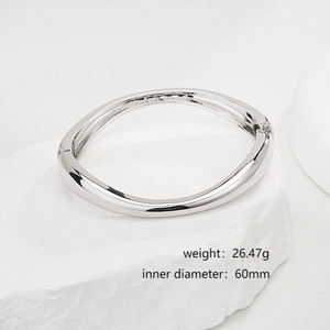 Minimalist silver irregular geometric bangle on white stone with polished finish