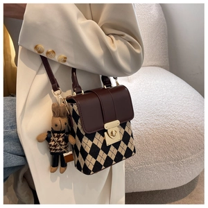 Detail of crossbody bag featuring brown flap, diamond pattern, and cute rabbit charm