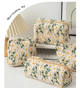 Detail of daisy embroidery on off-white canvas travel organizer and storage bags