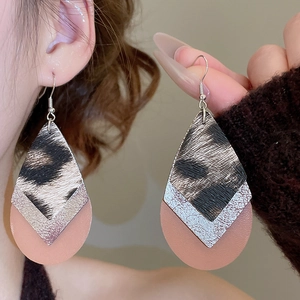 Close-up of layered leopard print and pink leather teardrop earrings with metal hooks