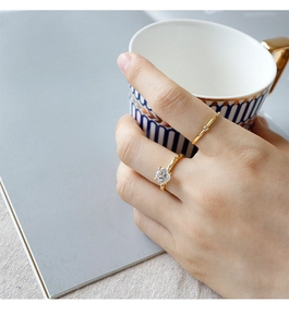 Close-up of dual-layered gold zircon rings worn while holding a blue striped cup