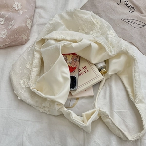 Top-down shot of white floral embroidery canvas tote bag with textured flower patterns