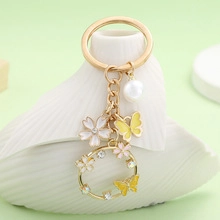 Close-up of gold butterfly keychain with pearl pendant and rhinestone cherry blossom