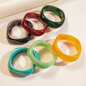 Stack of geometric resin bangles in six assorted marbled colors on a clean white background
