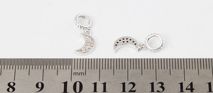 Detail of silver moon pendants with tiny inlaid zircons and a hollow star design back