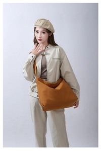 Dettaglio della grande borsa tote in tela marrone con struttura morbida e tracolla lunga