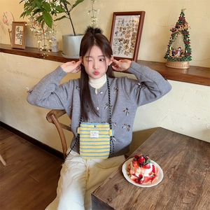 Asian woman in a cafe styling a small yellow and blue striped plush crossbody bag