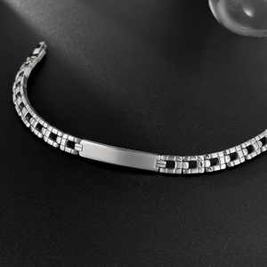 Macro detail of a silver stainless steel curb chain bracelet with a polished metal plate