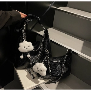 Detail of black embossed leather underarm bags with silver chains and plush cloud charms