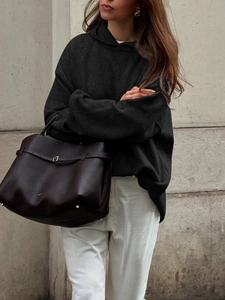 Close-up of black oversized hoodie paired with a large dark brown leather tote bag