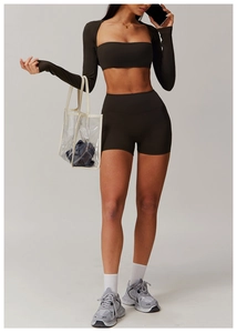 Three-piece dark brown yoga set featuring long sleeve shrug, sports bra and high waist shorts