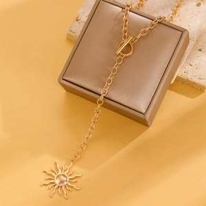 Dettaglio di una collana con ciondolo a sole dorato e chiusura OT su una pietra