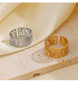 Detail of adjustable leaf pattern rings in gold and silver finish on stone surface