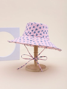 Detailed close-up of pink sun hat with blue heart patterns and matching bow tie strap