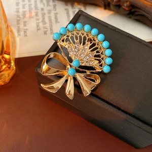 Macro detail of vintage gold fan brooch with sky blue beads and sparkling crystals