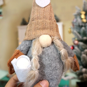 Close-up of a Christmas gnome doll with a heart pattern hat and long braided hair