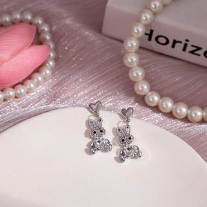 Détail de boucles d'oreilles lapin en argent avec cristaux et cœurs sur une assiette