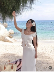 Detail of white puff sleeve crop top with V-neck tie detail and a matching long skirt