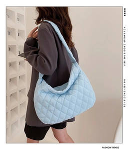 Detailed side view of light blue quilted tote bag on model for casual daily outfit