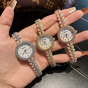 Close-up of three luxury quartz watches with pearl rhinestone straps in gold and silver