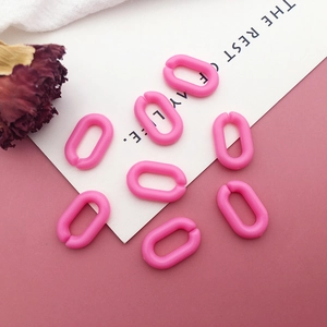 Flat lay of pink acrylic U-shaped chain links with decorative dried flower and card