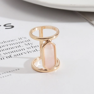 Detailed view of a gold geometric ring with a rectangular pink crystal on a white background