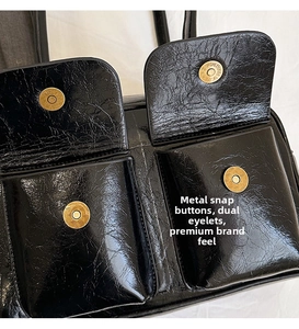 Detail of glossy black leather messenger bag with dual magnetic gold metal buckles