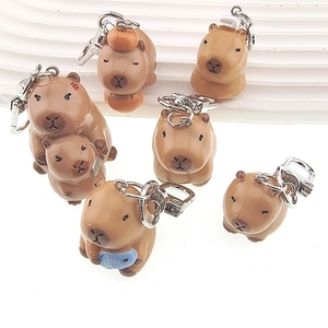 Close-up of cute 3D resin capybara keychains featuring orange and fish accessories