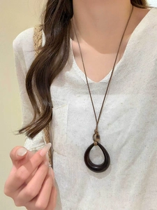 Detail of water-drop resin pendant on brown wax cord worn by model with V-neck top