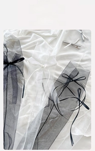 Detailed view of sheer mesh socks with sweet bow ribbons in black and cream colors