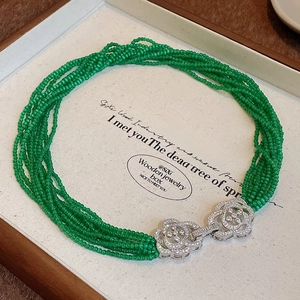 Macro view of vintage green beaded multi-layer necklace with floral rhinestone clasp