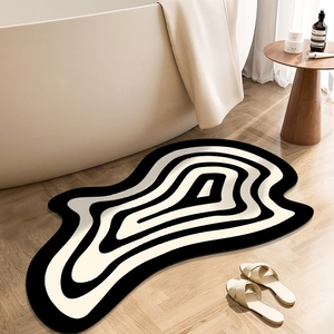 Detail view of wavy irregular bath mat in black and cream on bathroom wooden floor