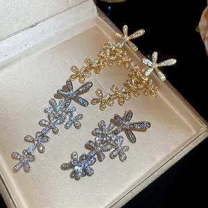 Sparkling zircon flower tassel earrings in 18K gold and silver finishes on a velvet box