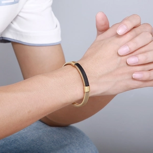 Detail of woven stainless steel men's bracelet in gold and black on a male wrist