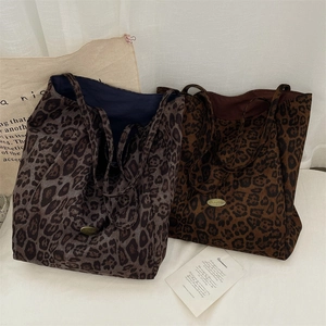 Detailed view of leopard print tote bags in brown and grey with metal logo and soft canvas texture