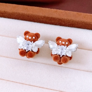 Macro detail of flocked teddy bear earrings with zircon wings in a jewelry box