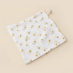 Detail of soft muslin baby washcloth with yellow floral pattern and hanging loop