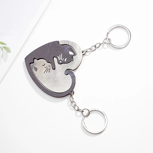 Detail of yin yang cat heart puzzle keychains in black and white finish on a white table