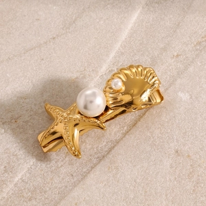 Macro detail of a golden starfish hair clip with glossy shell and white pearls