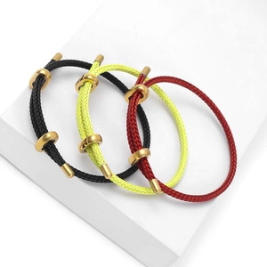 Three stylish woven rope bracelets in black, red, and yellow with gold metal accents