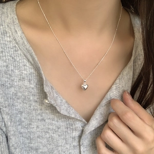Detailed close-up of a 925 sterling silver heart pendant necklace on a model's neck