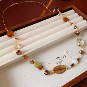 Detail of beaded long necklace with agate and white marble beads in a beige jewelry box