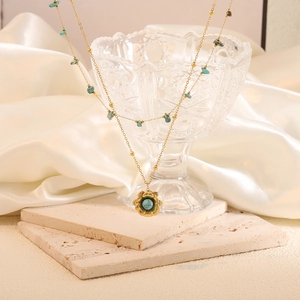 Golden double-layer turquoise necklace featuring flower pendant on natural stone chain