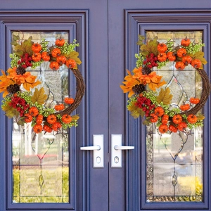 Autumn maple leaf wreath with pumpkins and berries on a dark door for home decoration