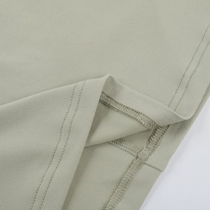 Detailed macro view showing the twin-needle hem stitching on green knit dress fabric