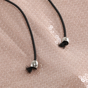 Detalle de lentejuelas de oro rosa sobre malla con cordón negro y puntas metálicas